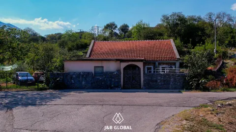 Pogled na tradicionalnu kuću sa dvorištem i kamenom ogradom pored puta. - image 5