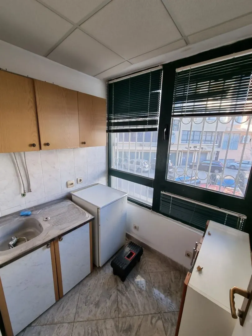 A small kitchen with wall cabinets, a sink, and a window.
