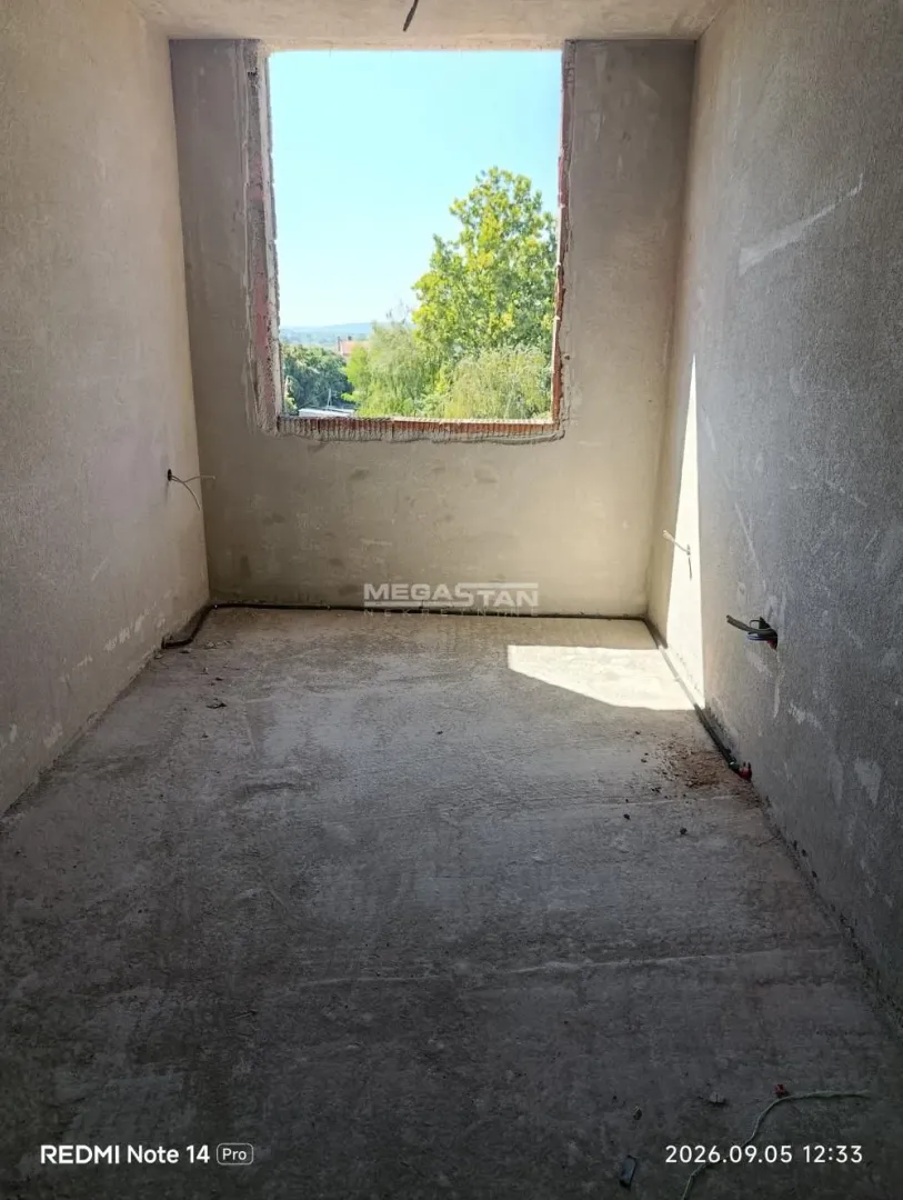 Unfinished room with a window and a view of greenery.