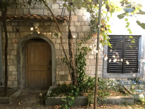 Kamena fasada stare kuće sa drvenim vratima i prozorom sa kapcima. - image 11