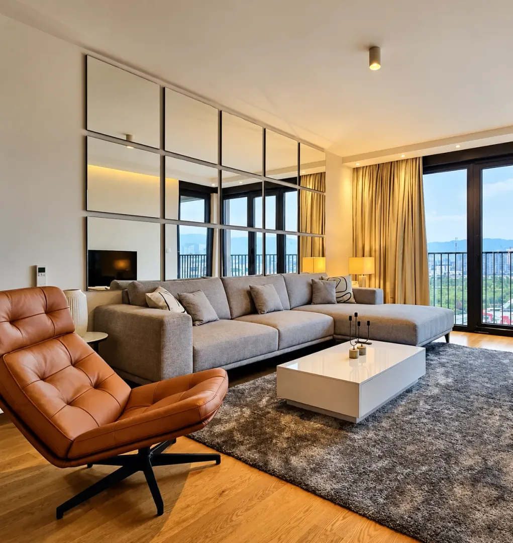 Modern living room with a sectional sofa, armchair, and wall mirrors.