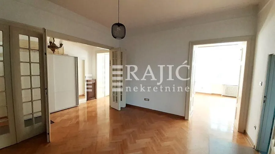 Empty room with parquet flooring and wooden double doors.