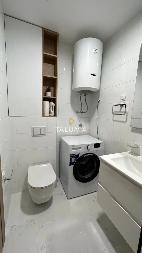 Modern bathroom with washing machine, toilet, water heater and sink.