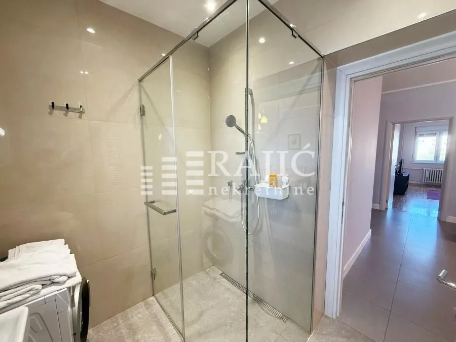 Modern bathroom with a shower cabin and glass partition.