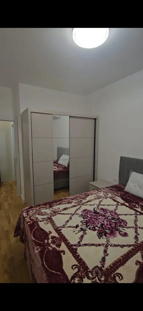 Namještena spavaća soba sa bračnim krevetom i garderoberom.