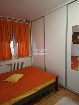 Bedroom with a double bed, large wardrobe, and orange curtains. - image 3