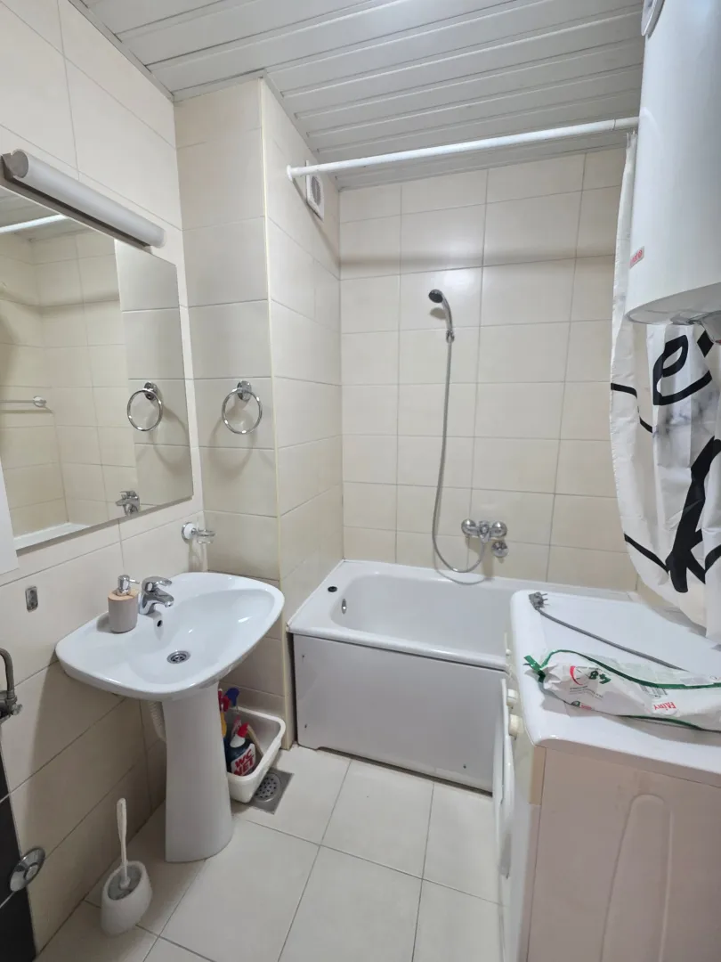 Manje kupatilo sa kadom, umivaonikom i veš mašinom.