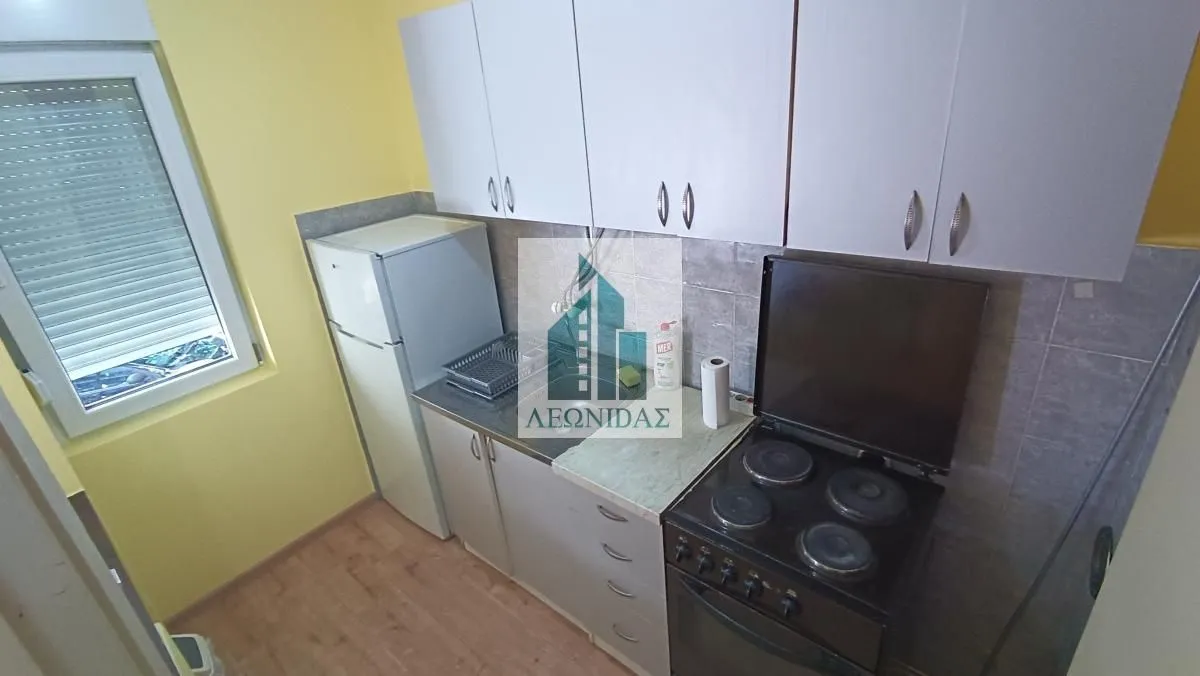 Small kitchen with white cabinets, refrigerator, and stove.