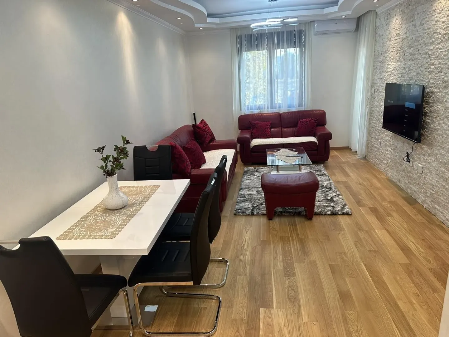 Bright living room featuring a dining table and red leather sofas.