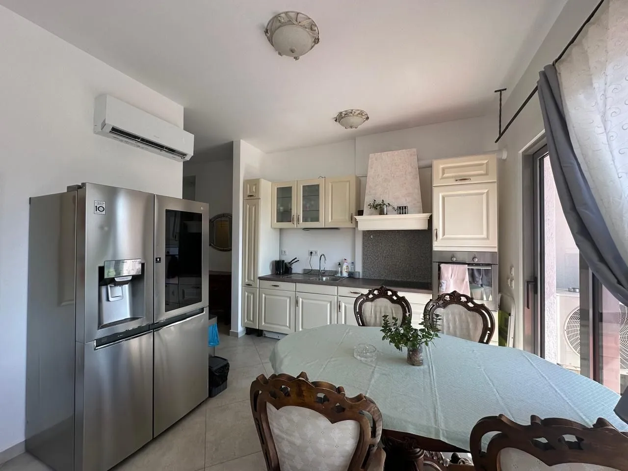 Spacious kitchen with a dining area, white cabinetry, and a large refrigerator.