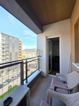 Natkriveni balkon sa stolicama i pogledom na okolne zgrade i grad. - image 8