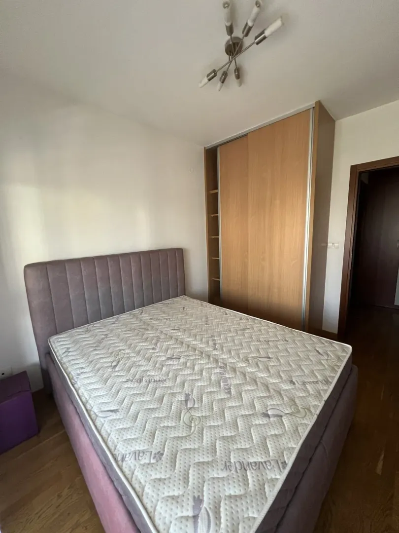 Spavaća soba sa bračnim krevetom i ugradnim drvenim plakarem.