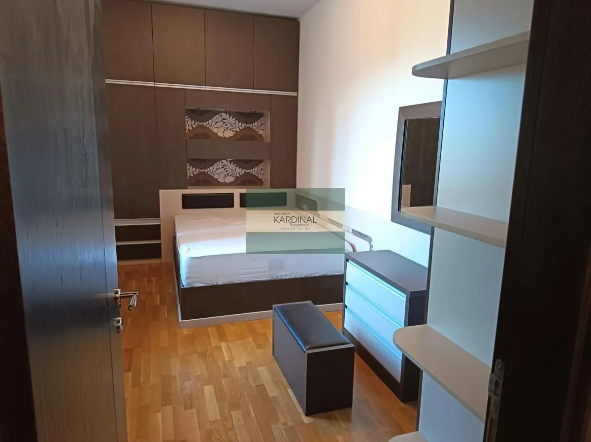 Pogled na spavaću sobu sa bračnim krevetom, garderoberom i drvenim podom.