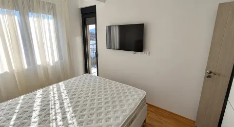 Bedroom with a bed, wall-mounted TV, and balcony access. - image 4