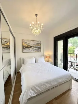 Bright and tidy bedroom with a double bed, large wardrobe, and balcony access. - image 3