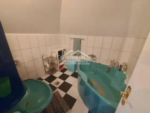 Kupatilo sa plavom kadom, umivaonikom i pločicama na zidu. - image 6
