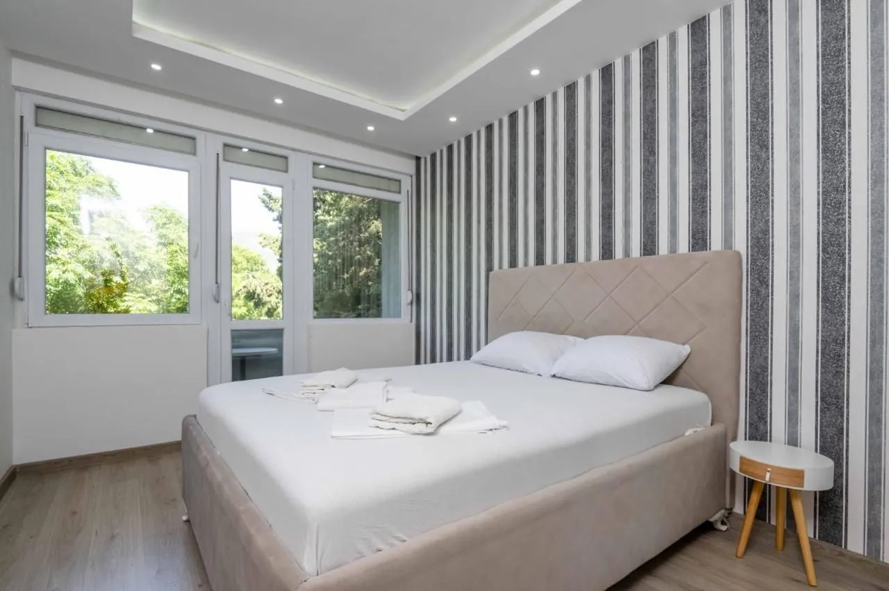Bright bedroom with a double bed, patterned wallpaper, and access to the terrace.
