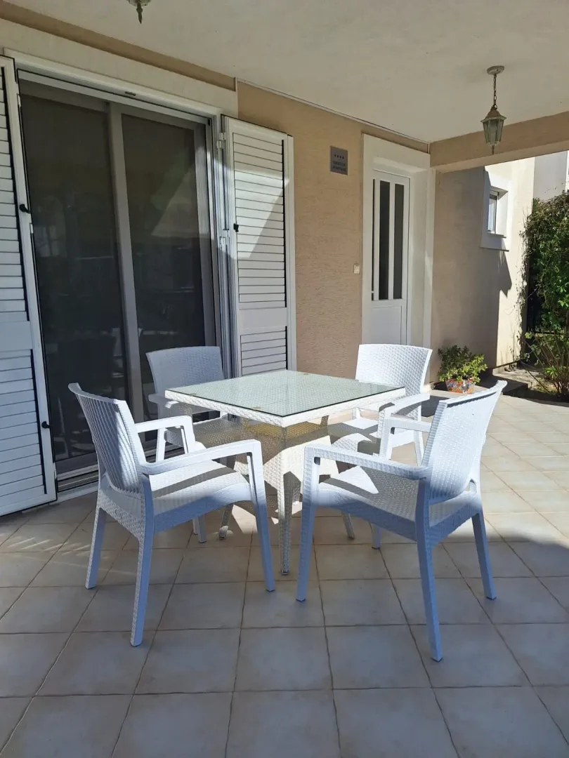 Covered terrace with seating furniture in front of the apartment entrance.