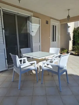 Covered terrace with seating furniture in front of the apartment entrance. - image 2