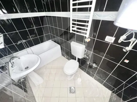 Bathroom equipped with a bathtub, washbasin, toilet, and white floor tiles. - image 14
