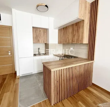 Moderna kuhinja sa belim elementima, drvenim detaljima i šankom. - image 6
