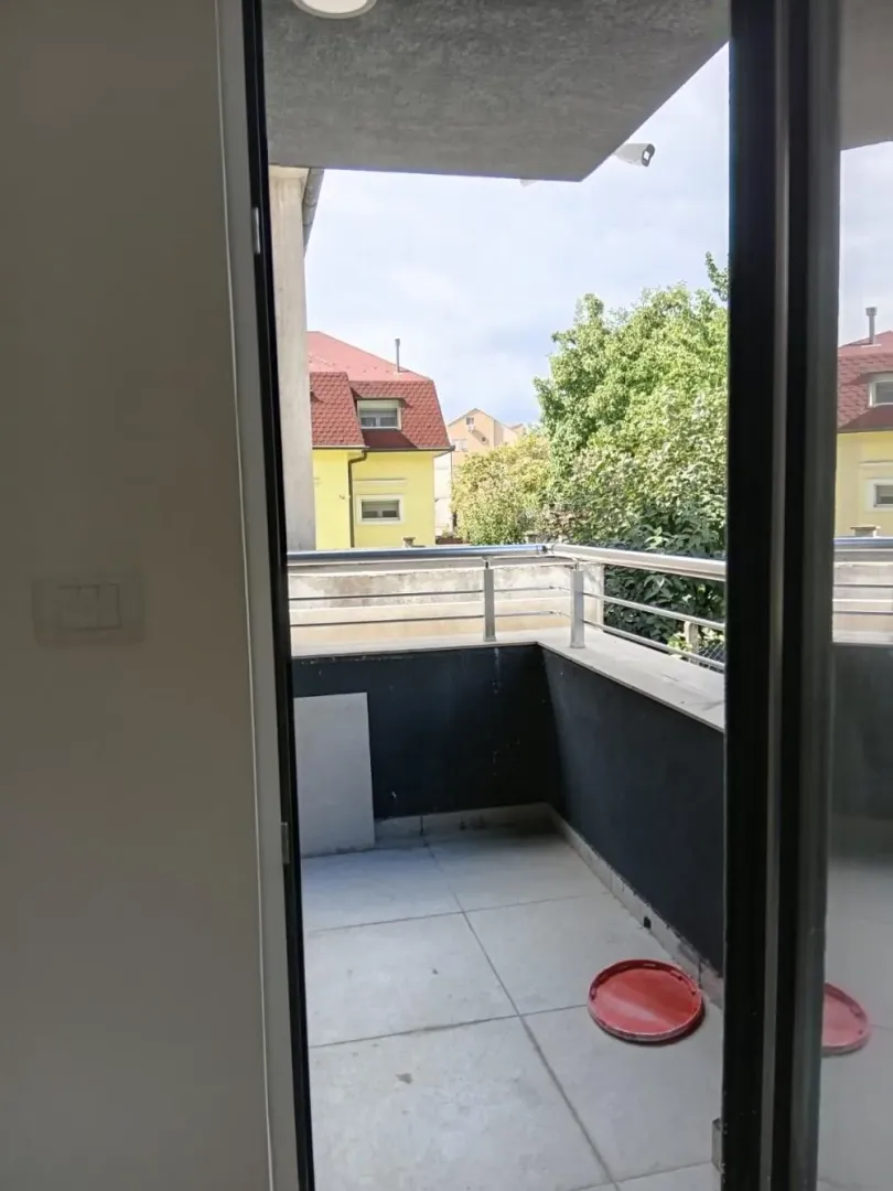 Pogled iz stana na otvorenu terasu sa metalnom ogradom.