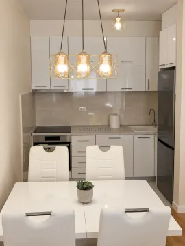 Modern white kitchen with a dining table and built-in appliances. - image 2