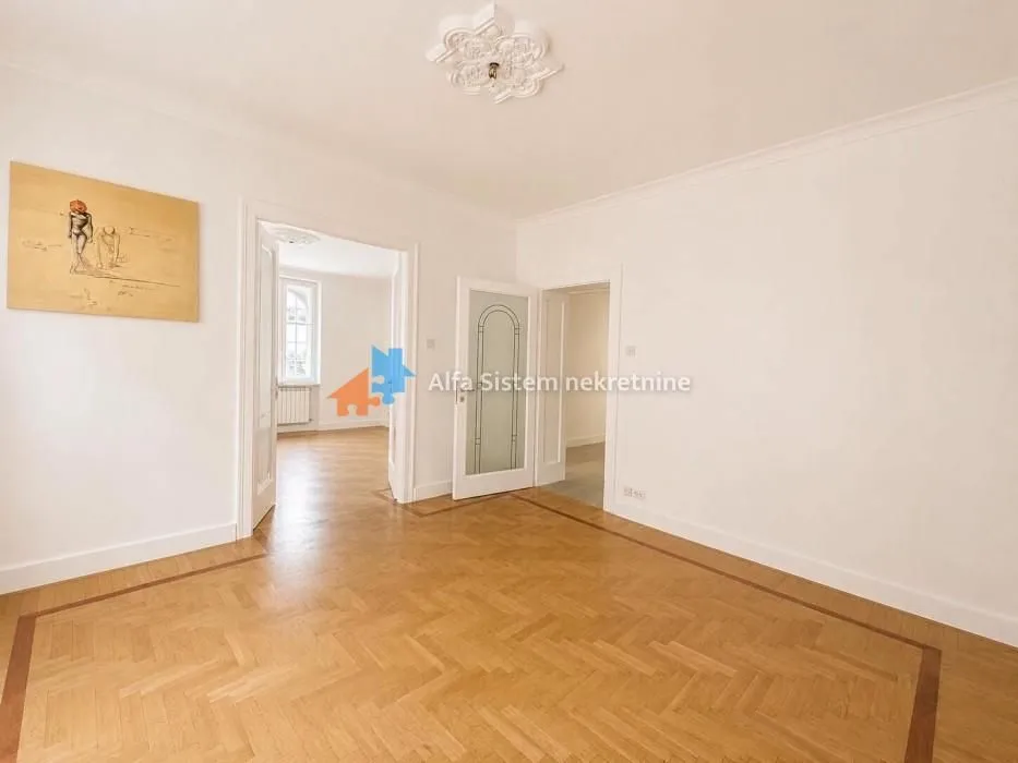 Empty room with wooden parquet flooring and decorative ceiling plaster molding.