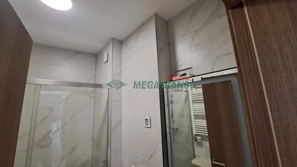 Pogled na kupatilo sa tuš kabinom obloženim mermernim pločicama.