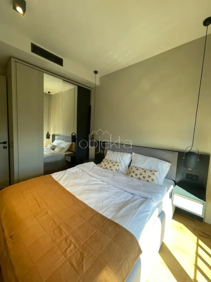 Modern bedroom with a double bed, built-in wardrobe, and hanging lights.