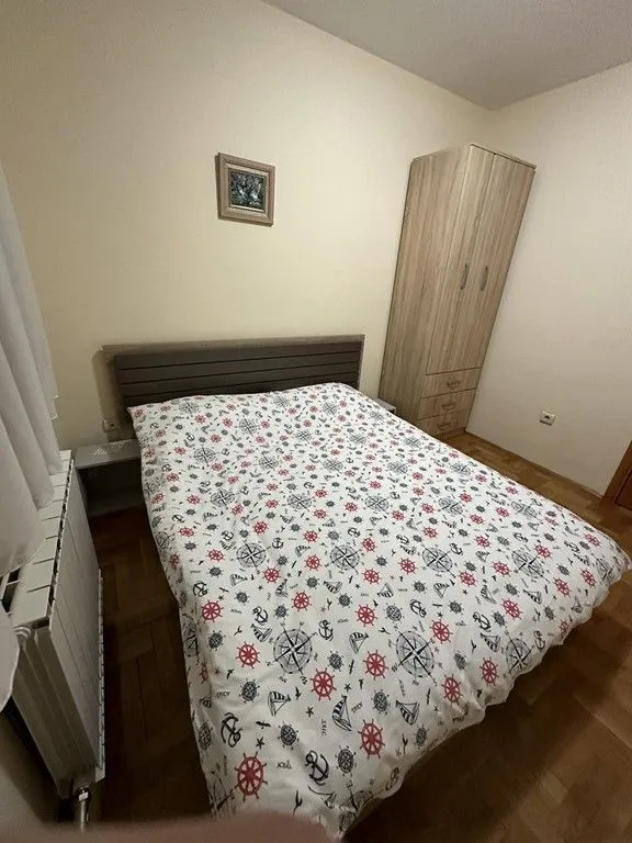 Namještena spavaća soba sa bračnim krevetom i ormarom.