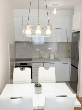 Moderna kuhinja sa bijelim elementima i trpezarijskim stolom. - image 6