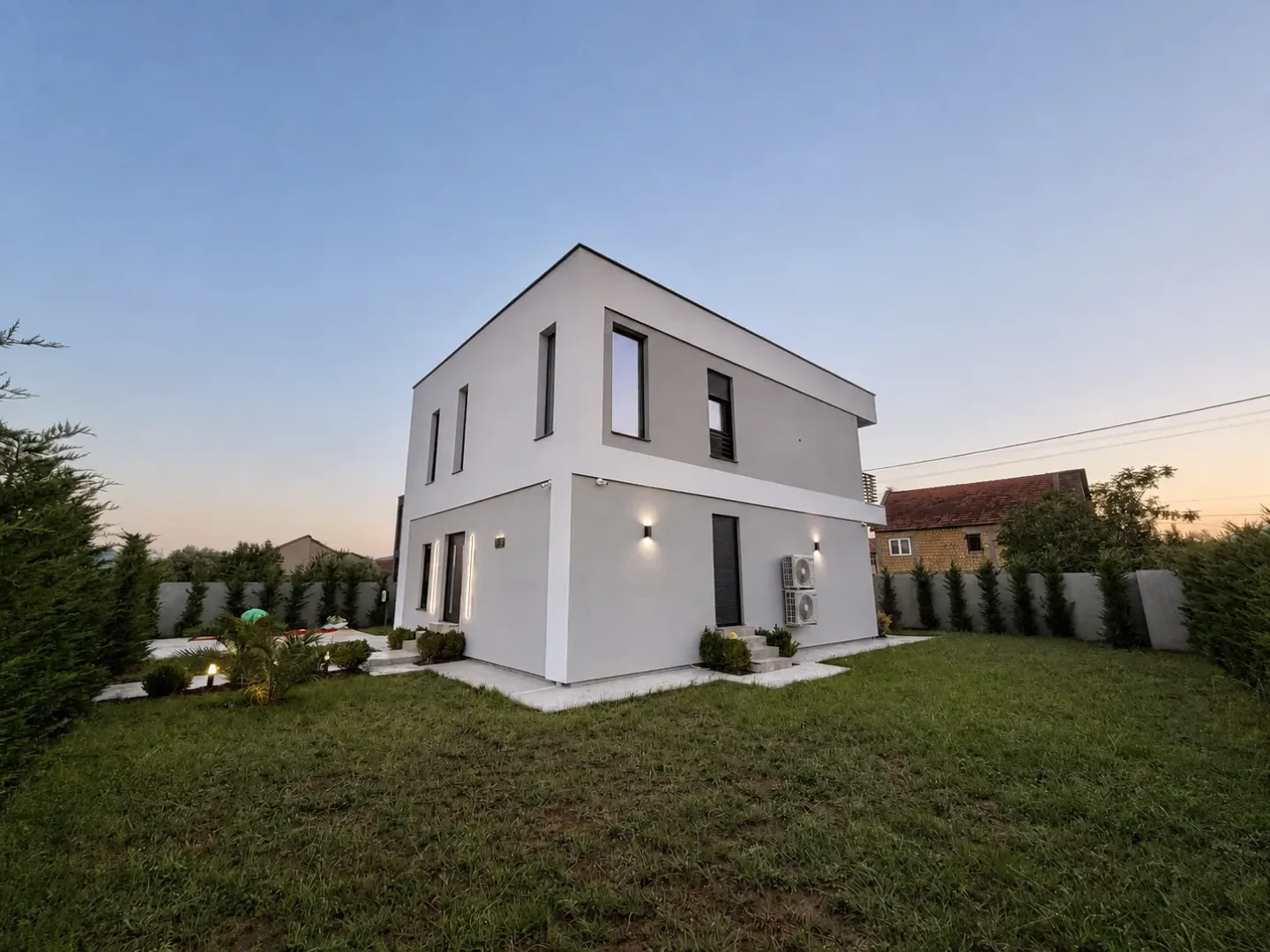 Exterior view of a two-story house with a landscaped yard and lawn.
