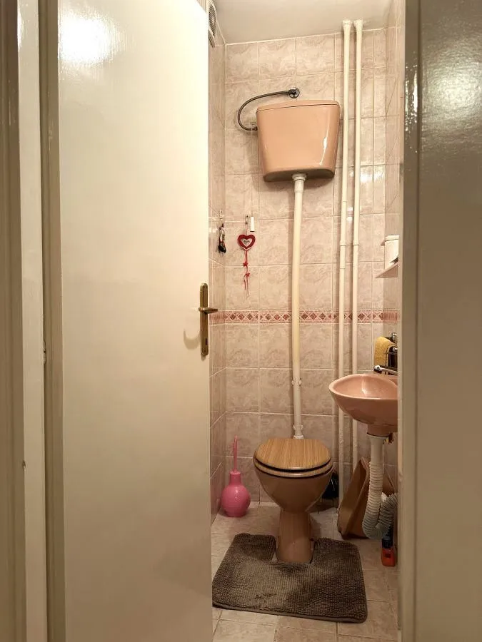 Small tiled bathroom with a toilet and a sink.