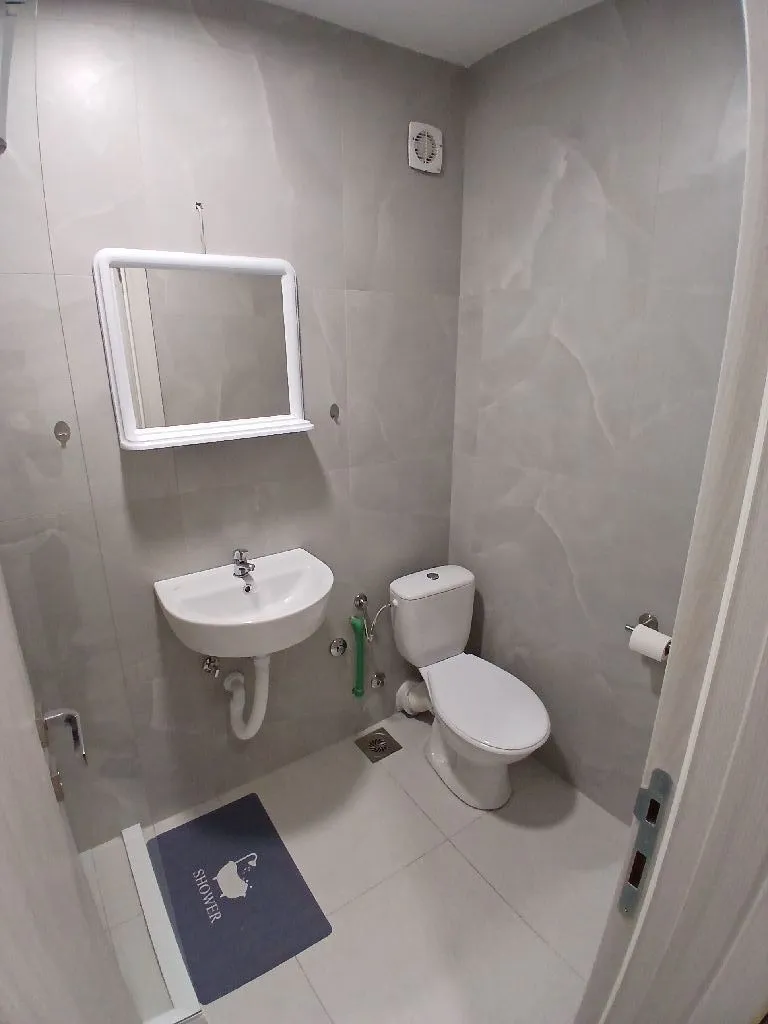 Small bathroom tiled in gray with a sink and toilet.