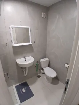 Small bathroom tiled in gray with a sink and toilet. - image 9