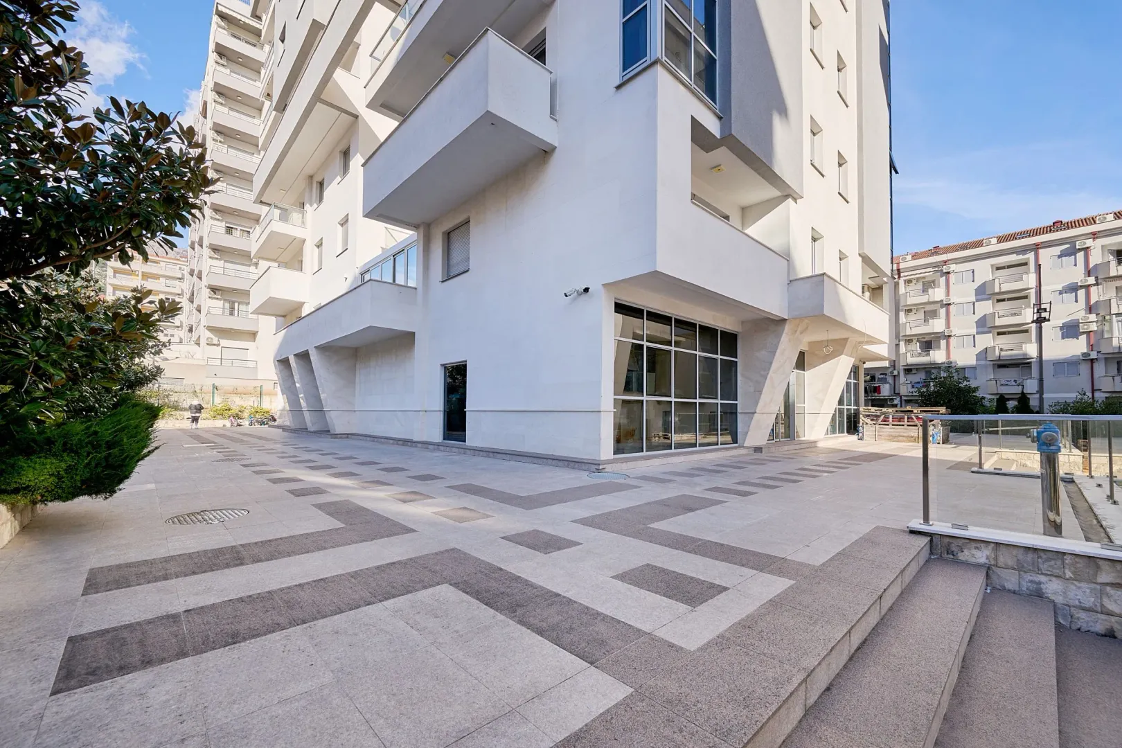 Vanjski izgled moderne stambene zgrade sa popločanim platoom.