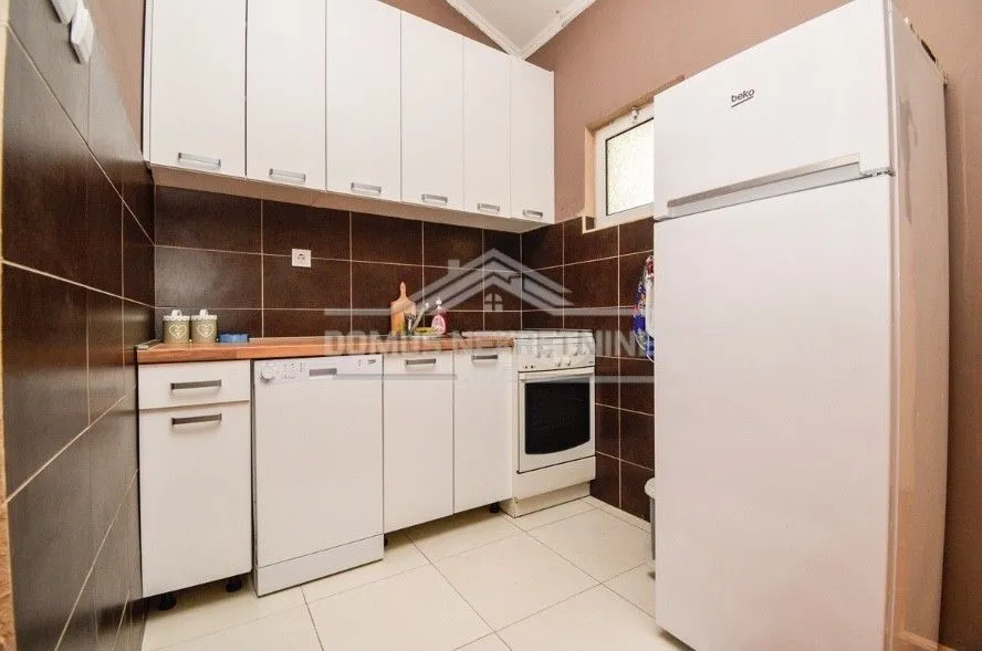 A simple kitchen featuring white cabinetry and a refrigerator.