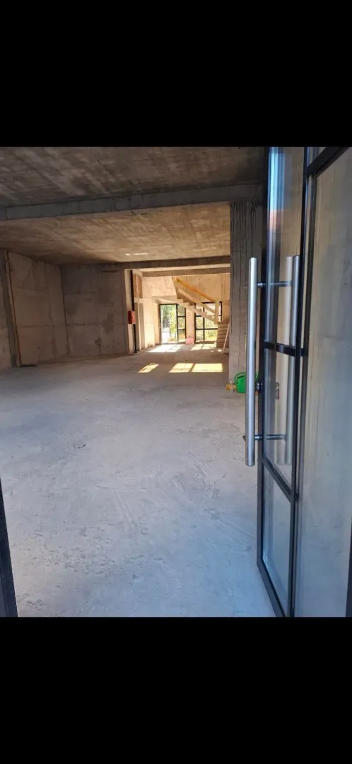 Interior of an unfinished bare-shell space with glass entry doors.