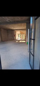 Interior of an unfinished bare-shell space with glass entry doors. - image 4