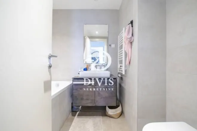 Modern bathroom equipped with a washbasin, mirror, and bathtub.