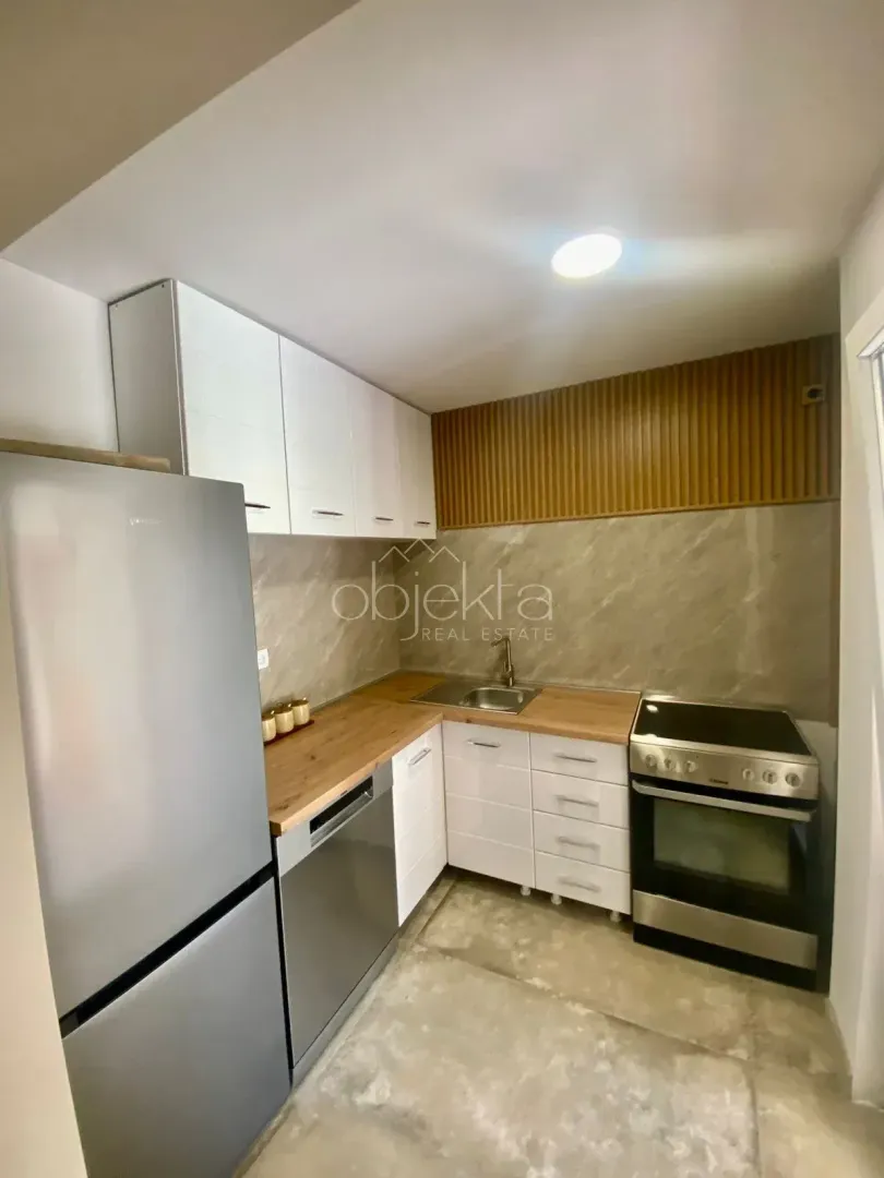 Small modern kitchen with white cabinets and a wooden countertop.
