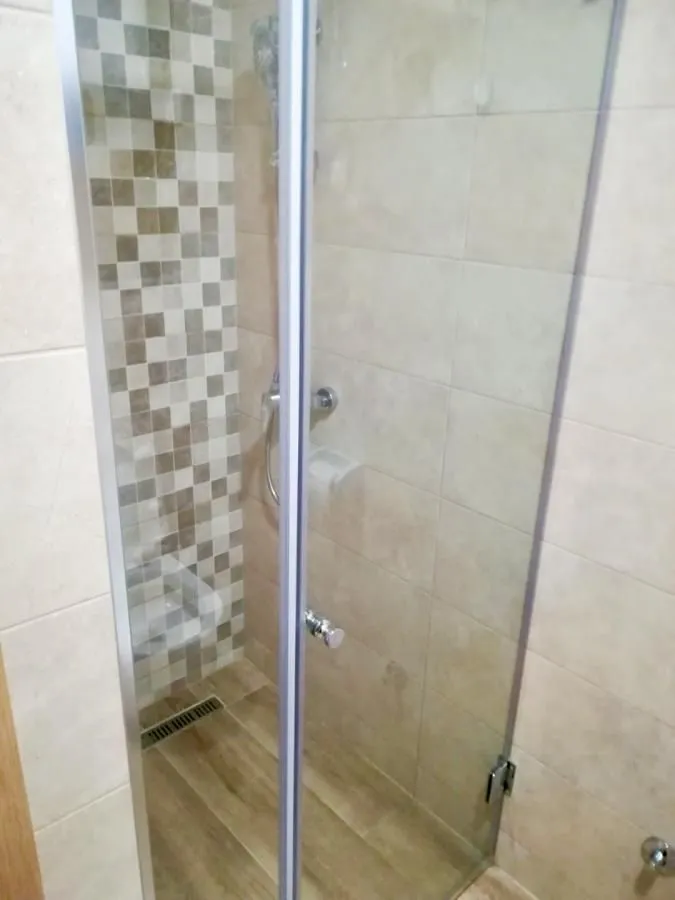 Shower cabin with glass door and ceramic tiles in the bathroom.