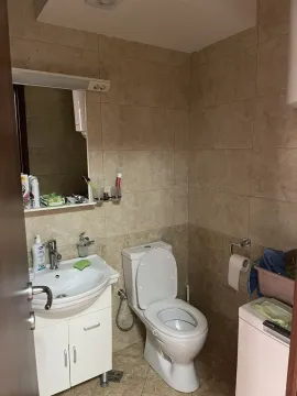 Jednostavno kupatilo sa bež pločicama, lavaboom i toaletom. - image 9