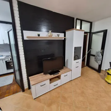 Living room with a TV and chest of drawers against a black wooden accent wall. - image 2