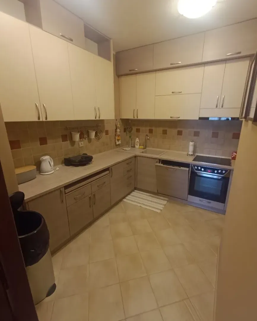 Potpuno opremljena kuhinja sa svijetlim elementima i keramičkim pločicama.