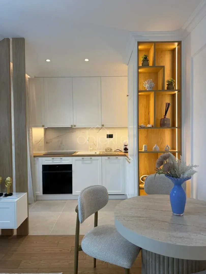 Modern kitchen with white units and a dining table.