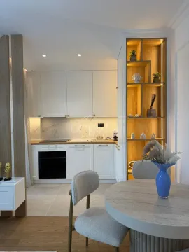 Modern kitchen with white units and a dining table. - image 7