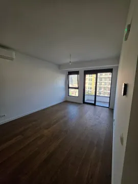 Prazna soba sa tamnim drvenim podom i izlazom na terasu. - image 8