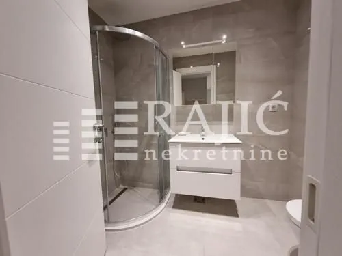 Modernly equipped bathroom with a shower cabin and sink.